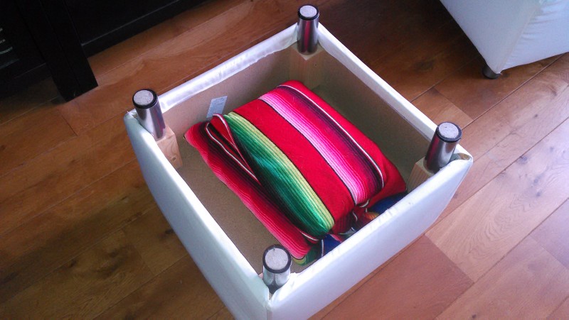 ottoman upside down with two blankets, both folded over hot pot