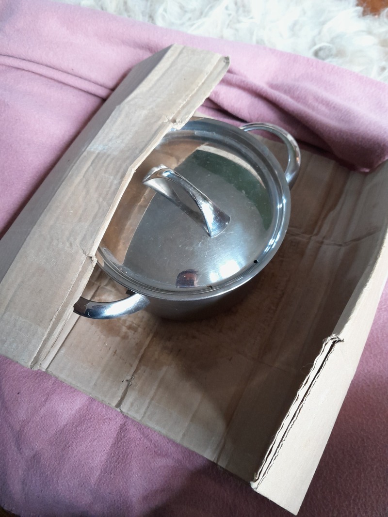 pan with boiling rice covered with a lid placed on top a piece of cardboard