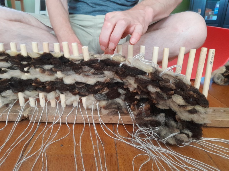 Sliding the woven piece down the warp threads.