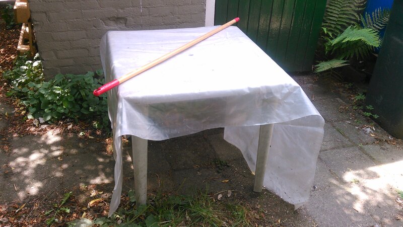 Table with plastic sheet and broomstick.